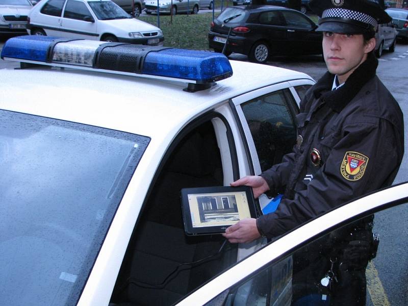 Strážník ukazuje tablet, který je součástí radaru ve služebním vozidle. 