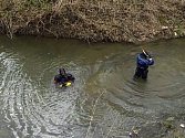 Policisté prohledávali dno řeky Lučiny v Havířově. Potápěč drží nalezený předmět.