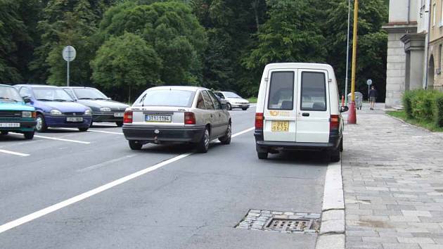 Řidiči projíždějící ulicí Na Nábřeží musejí počítat s parkujícími vozidly, s prohlubněmi u kanálů a občas také s bezohlednými pošťáky.