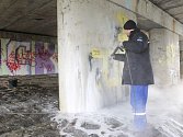 Jeden ze zaměstnanců firmy Nanoteam pracuje na odstranění graffiti pod mostem na Ratibořské ulici v Opavě.