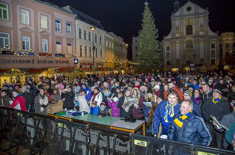 S úderem šesté hodiny se první koleda Nesem vám noviny začala zpívat také na Dolním náměstí v Opavě. Nemohl ji uvést nikdo jiný než známý sbormistr z Nového Dvora Karel Kostera, jenž na pódiu vedl členy stěbořického a také opavského sboru. 