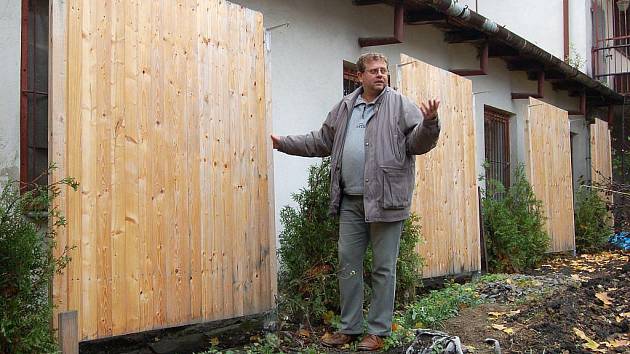 Josef Jakubec stojí před dřevěnými zábranami, které jeho sousedé postavili před okna pekárny na Dělnické ulici.