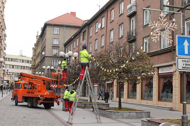 Pracovníci technických služeb zavěšují vánoční ozdoby na Hrčířské ulici v Opavě.