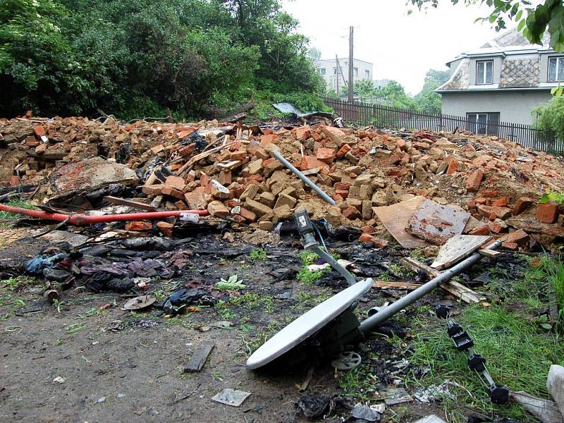 Cedulky Zákaz vstupu. Ticho. Klid. Ani ptáci sem nelétají. I méně citlivý nos cítí spáleninu. Tady stál vítkovský dům číslo 58. Hromada stavební suti, několik ohořelých trámů, satelitní anténa v trávě, ohněm zčernalé nůžky, támhle leží bota. 