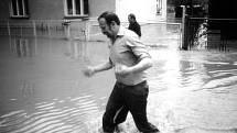 Dva muži ze Smolkova, jejichž domovy jsou již zaplaveny, se brodí špinavou vodou.