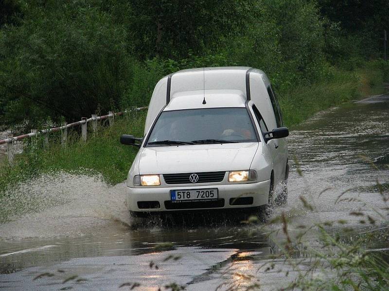 Řeka Opavice u Města Albrechtic se naplnila až po okraj, voda se dostala i na silnici.
