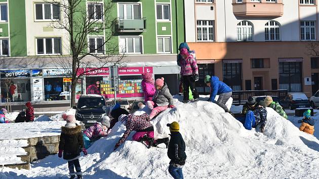 Krnovské děti radostně dovádí na hromadě sněhu přímo na náměstí.