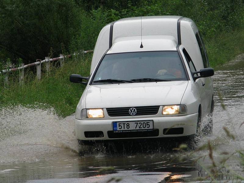 Řeka Opavice u Města Albrechtic se naplnila až po okraj, voda se dostala i na silnici.