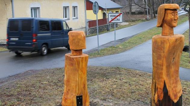 Dřevěné postavy vítají návštěvníky Železné, místní části Vrbna pod Pradědem. Dvě stojí na křižovatce, dvě u prodejny a jedna u zastávky.