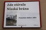 Tady v těchto místech se v historii vstupovalo branou za hradby města Bruntálu. V historii zbořené městské brány nyní připomínají v Bruntále informační cedule. V základech jedné brány byl nalezen kámen s vročením 1109, tedy ještě o sto let dříve, než byl 