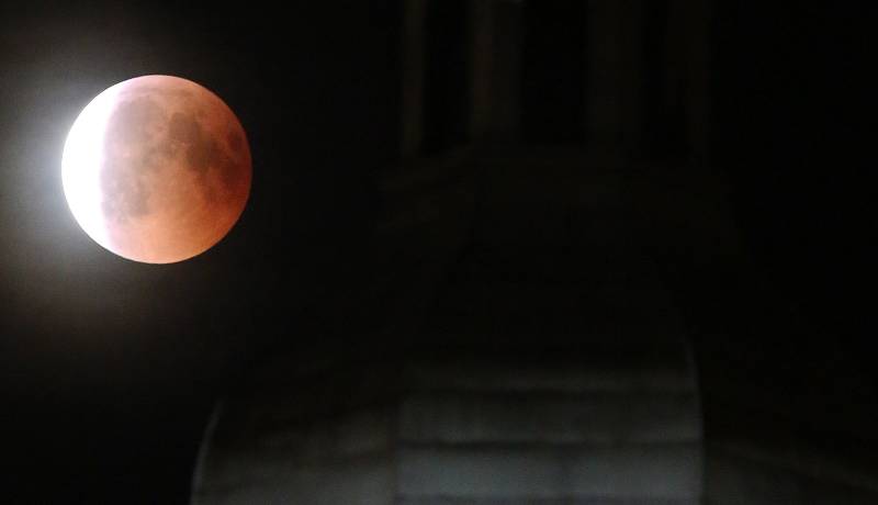 Pohled na úplné zatmění měsíce nad hradem Hazmburk a Litoměřiceme. Letošní oblačnost nepřála obdivovatelům vesmírného divadla a měsíc se objevil na oblože už téměř celý zahalený stínem.