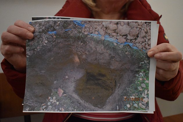 Jana Ulrychová na chodbě u okresního soudu v Děčíně ukazuje snímek z výkopu hrobu, kde nenašla svou dceru.