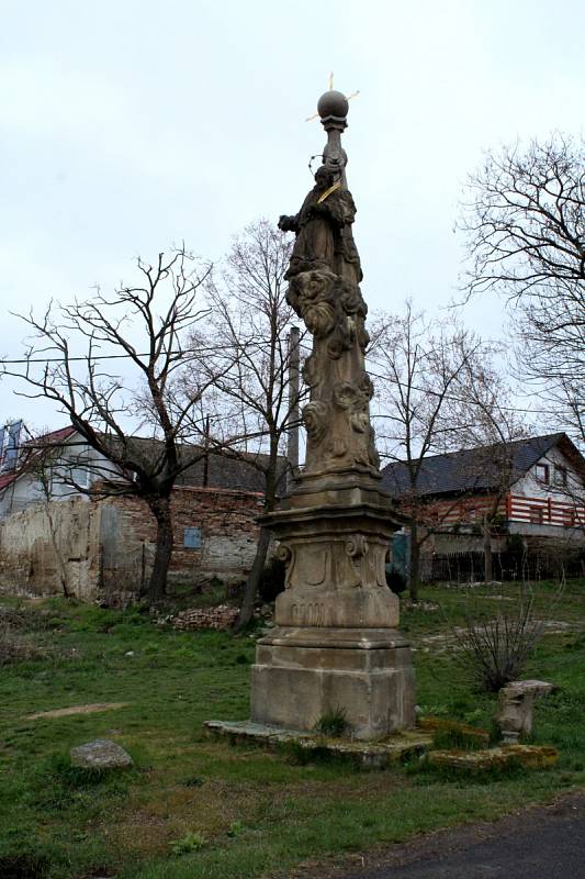 Na návsi v obci Škrle najdete kostelík a na sloupku posezení kešku.