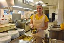 Než se do jídelny nahrnou žáci, plní kuchařky jídlonosiče pro strávníky zvenčí. Na snímku je Olesia Mak.