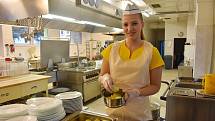 Než se do jídelny nahrnou žáci, plní kuchařky jídlonosiče pro strávníky zvenčí. Na snímku je Olesia Mak.