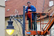 Pracovník technické správy instaluje vánoční výzdobu v ulicích Chomutova