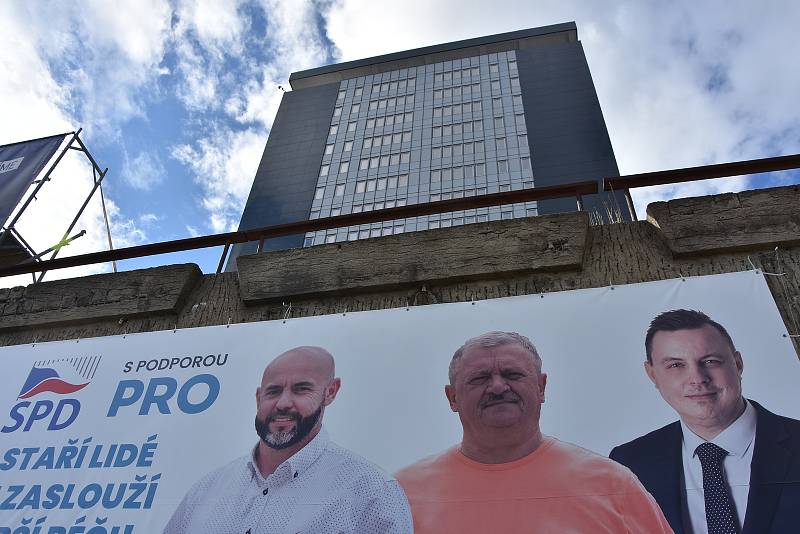Ladislav Kosán (v oranžovém tričku) na billboardu chomutovské SPD v patě Armabetonu. Budova stojí na pozemku firmy SADETO Consulting SE, ve které patří sedmdesát procent akcií manželce Alexandra Nováka.