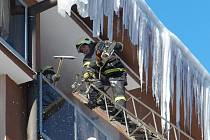 Na snímku jeden z vejprtských dobrovolných hasičů ze žebříku odstraňuje motorovou pilou zledovatělé rampouchy ze střechy domu. Pokud by se některý uvolnil, mohl by pádem na chodník ohrozit procházející chodce.
