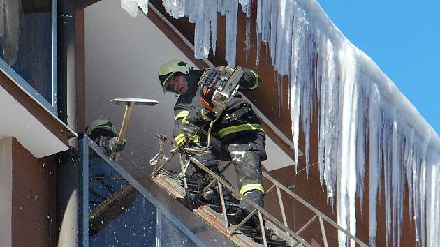 Na snímku jeden z vejprtských dobrovolných hasičů ze žebříku odstraňuje motorovou pilou zledovatělé rampouchy ze střechy domu. Pokud by se některý uvolnil, mohl by pádem na chodník ohrozit procházející chodce.