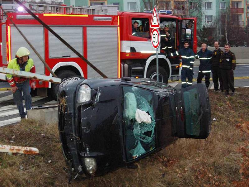 Jeřáb vytahuje auto z příkopu za asistence hasičů