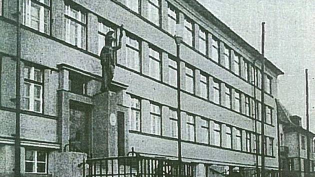 Socha Pallas Athény nad vchodem do chomutovského gymnázia na fotografii z roku 1933.